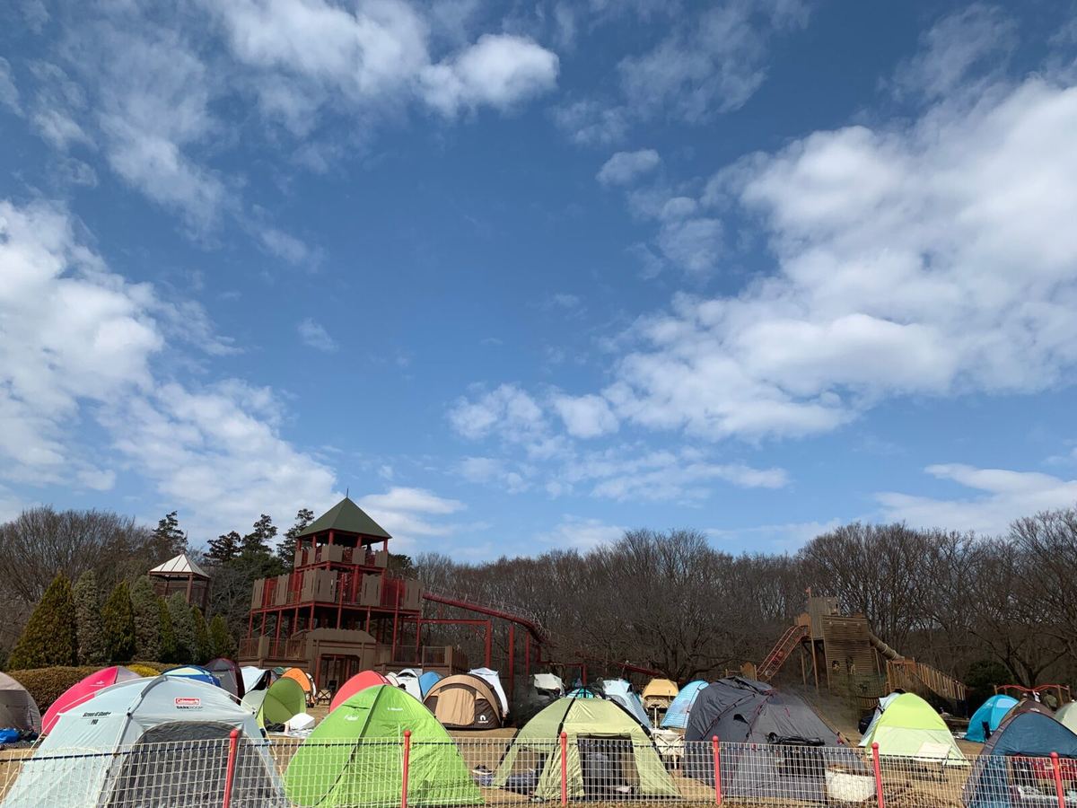 A wide view of the athletic play area with its wooden tower and rows of colorful family tents