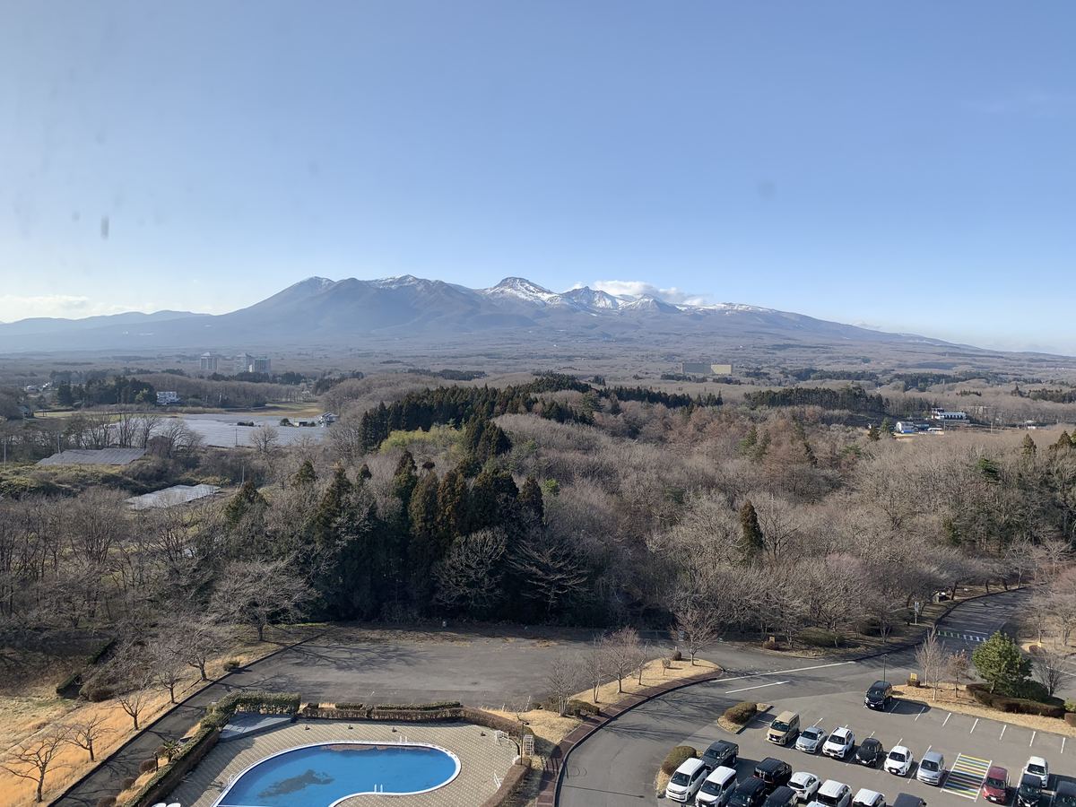 View of the snow-capped Nasu mountains from an upper floor of Grand Mercure Nasu Highlands, with the resort's outdoor pool and grounds below