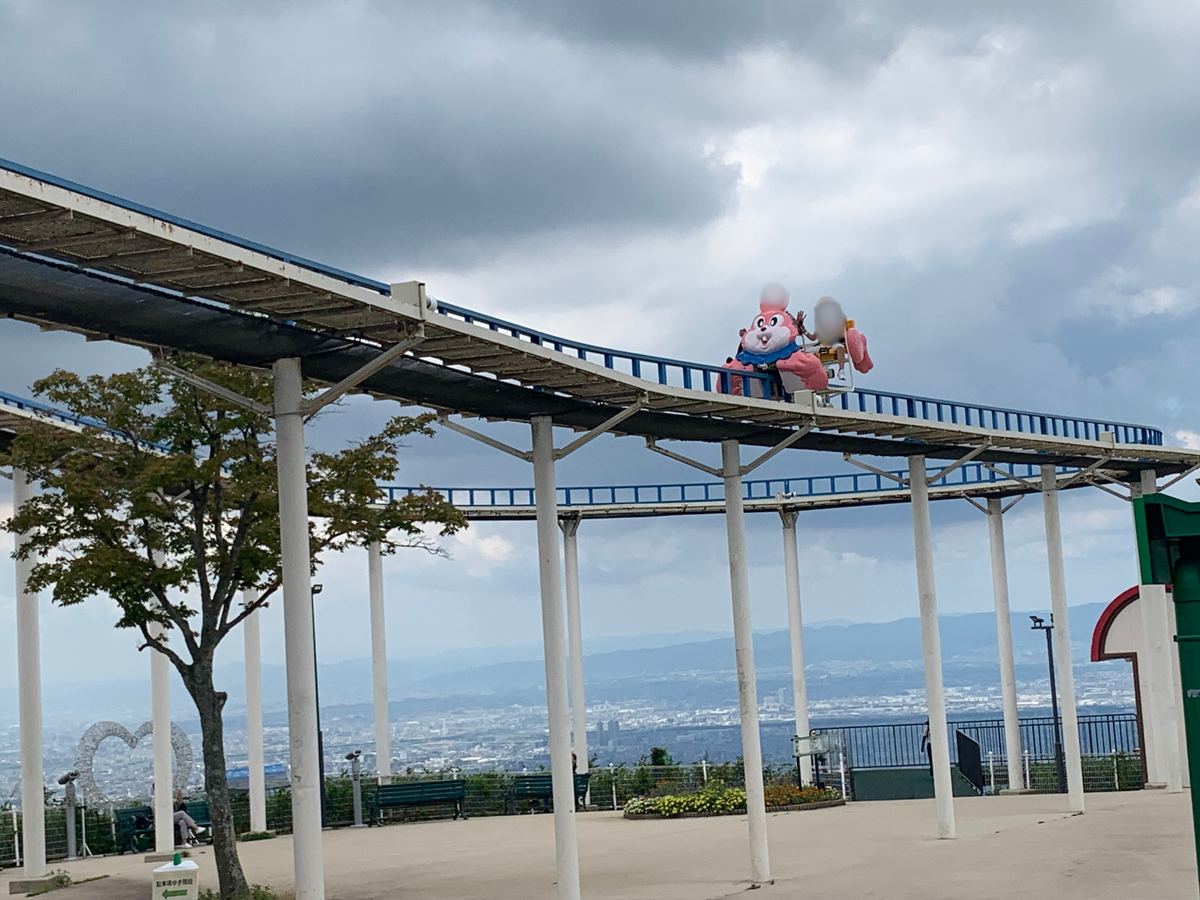 A kids' roller coaster on an elevated track with the Osaka Plain stretching out far below